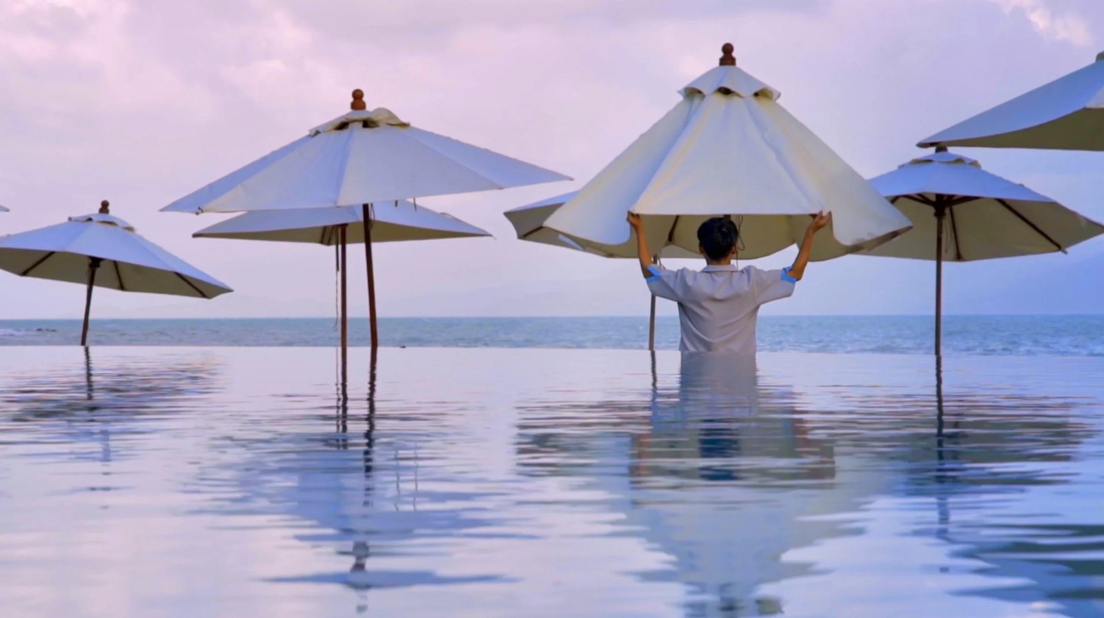 Melati Beach Resort & Spa — a guest in the infinity pool at dusk