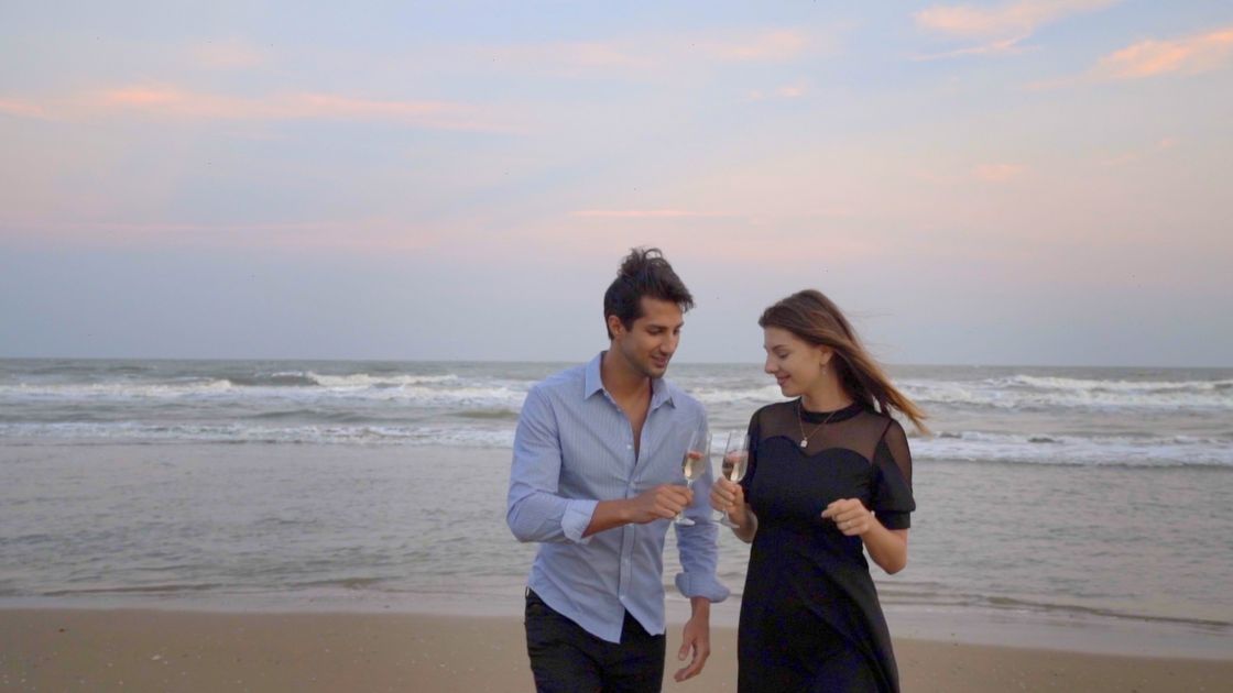 A couple walk the shoreline at golden hour