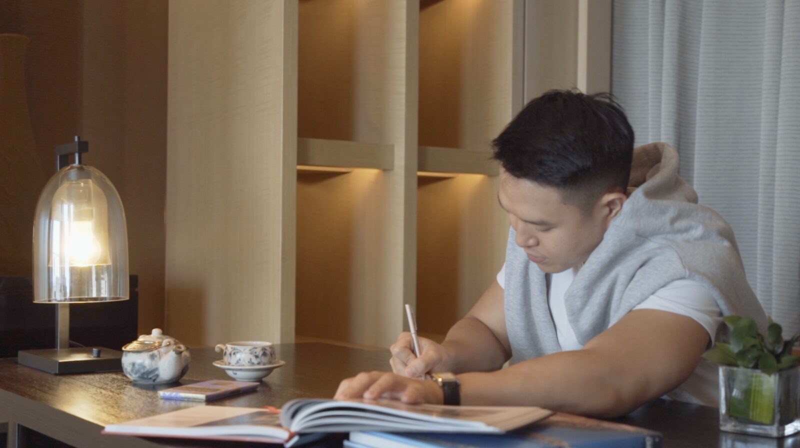 A guest writing at the desk in warm lamplight, New World Saigon