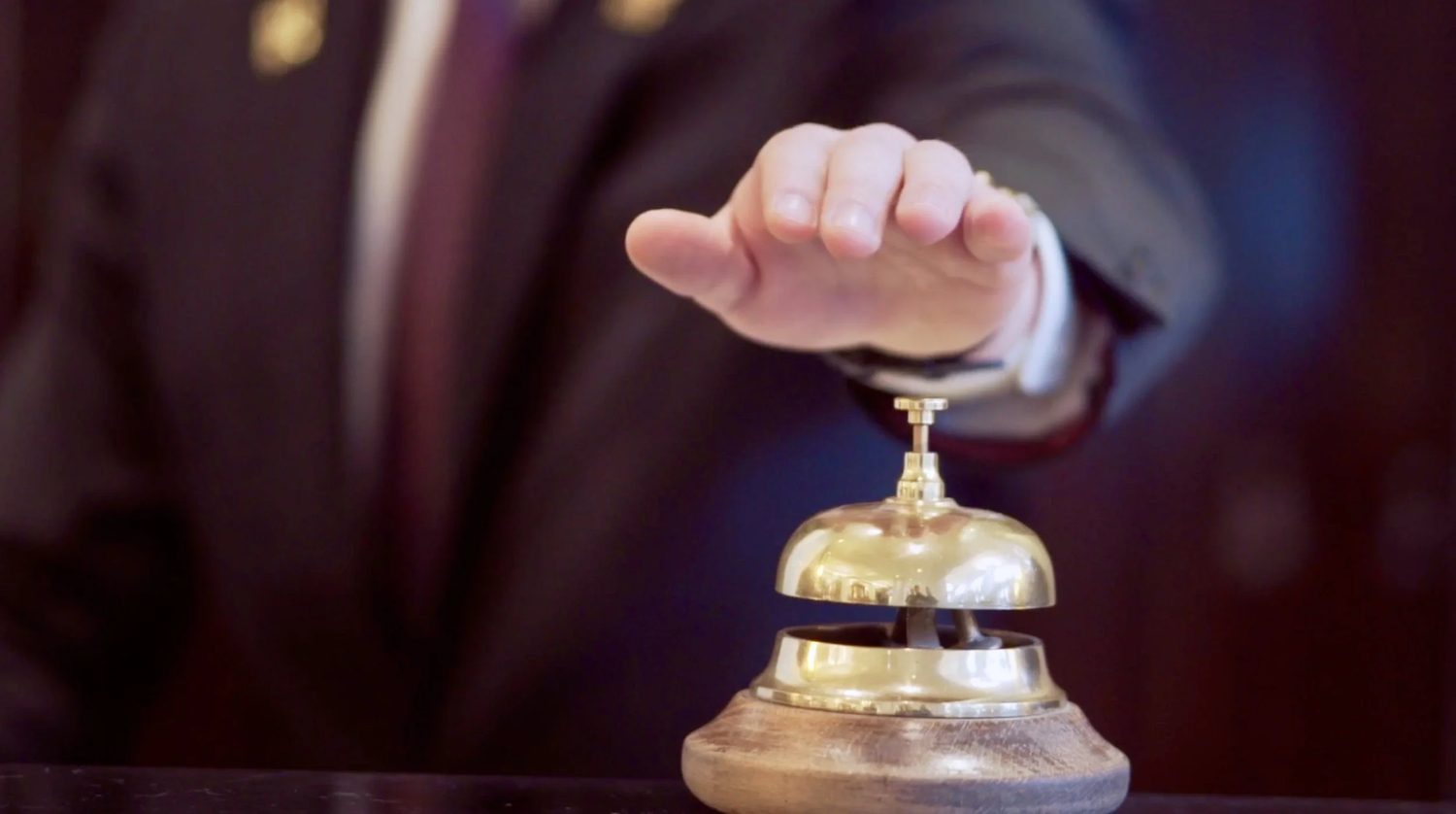 A hand at the front-desk bell